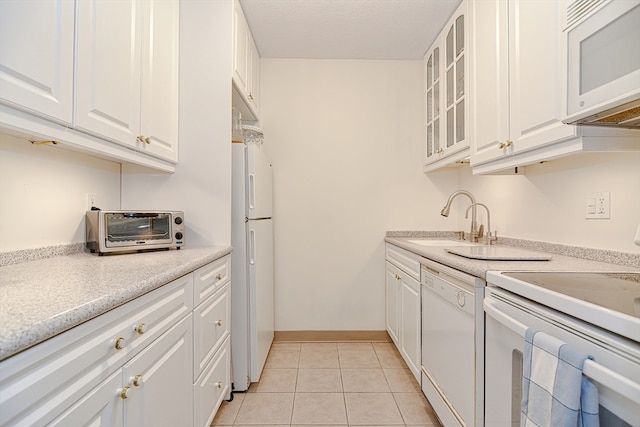 kitchen featuring white cabinets, white appliances, light tile patterned flooring, and sink