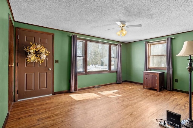 foyer featuring light hardwood / wood-style flooring, crown molding, a wealth of natural light, and ceiling fan