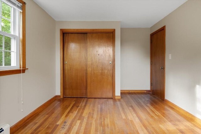 479 W, West Bridgewater, MA 02379 - unfurnished bedroom featuring light wood-style floors, a baseboard radiator, a closet, and baseboards