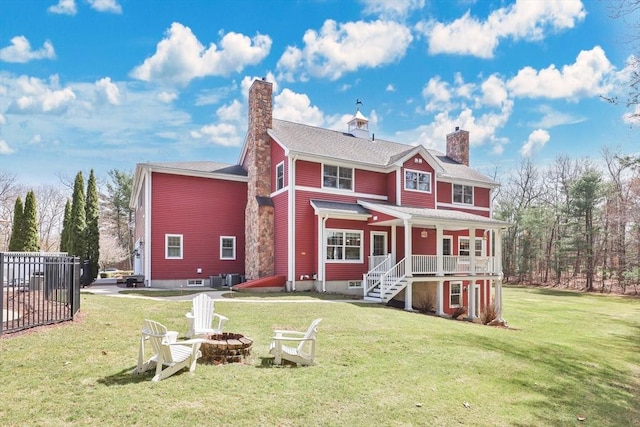 back of house with a yard, a fire pit, central air condition unit, and a chimney
