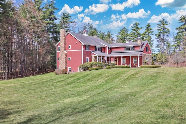 view of front of house featuring a front yard, a chimney, and covered porch