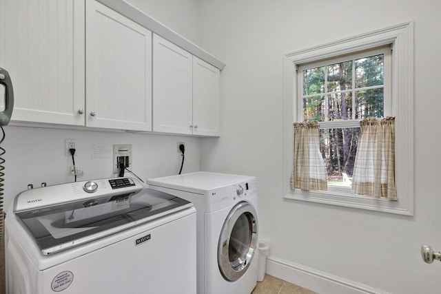 clothes washing area featuring washer and dryer, light tile patterned flooring, baseboards, and cabinet space