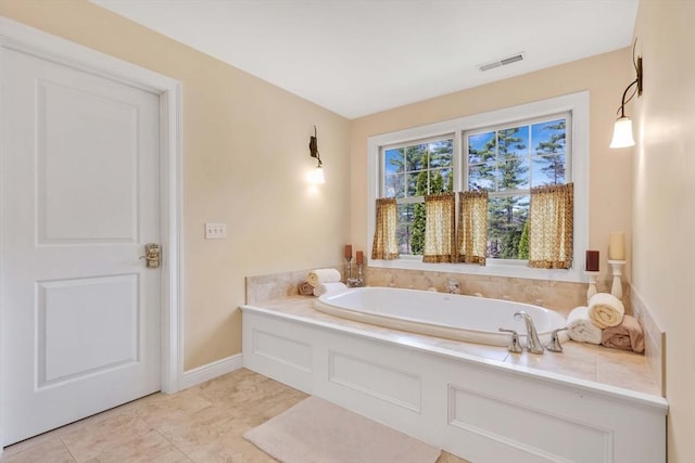 bathroom featuring visible vents, a bath, tile patterned flooring, and baseboards