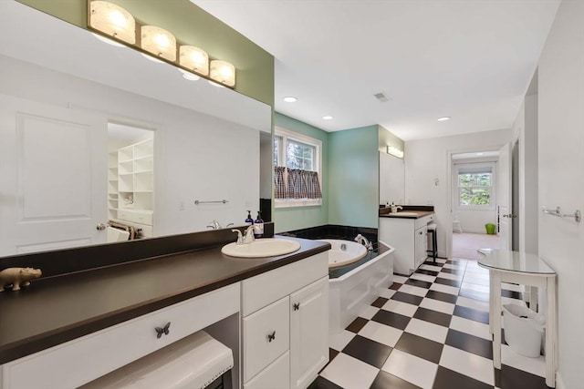 full bathroom featuring two vanities, tile patterned floors, a sink, and a healthy amount of sunlight