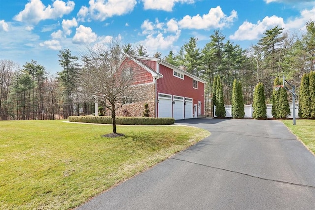 view of property exterior featuring a yard, a garage, stone siding, and aphalt driveway