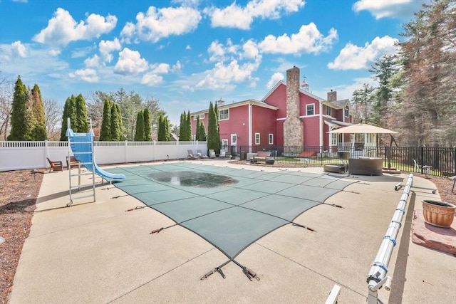 view of swimming pool featuring a patio area, a water slide, fence, and a fenced in pool