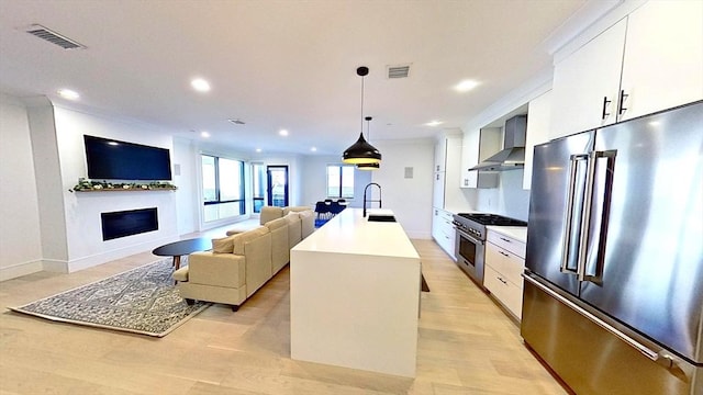 148 W 9th St Unit 6, Boston, MA 02127 - kitchen featuring high quality appliances, wall chimney range hood, a fireplace, white cabinets, and light countertops