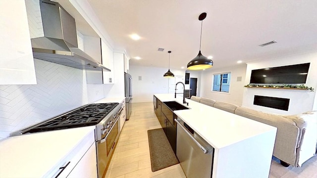 148 W 9th St Unit 6, Boston, MA 02127 - kitchen featuring wall chimney exhaust hood, stainless steel appliances, open floor plan, white cabinetry, and a kitchen island with sink