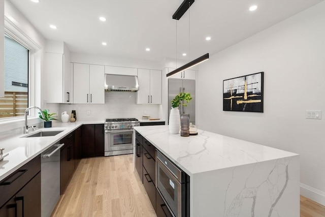 7 Johnson Pl Unit 7, Newton, MA 02466 - kitchen with high quality appliances, exhaust hood, a center island, white cabinets, and light wood-style flooring