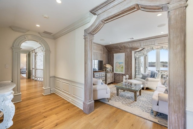 living room with crown molding, decorative columns, and light hardwood / wood-style floors