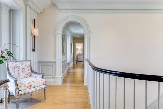 hall featuring ornamental molding, light hardwood / wood-style floors, and ornate columns