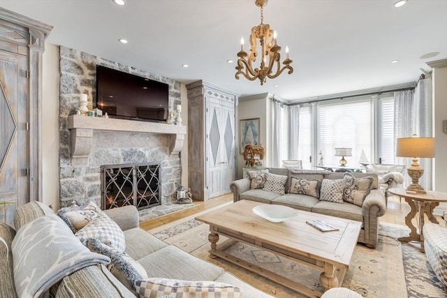 living room with an inviting chandelier, ornamental molding, a fireplace, and light wood-type flooring