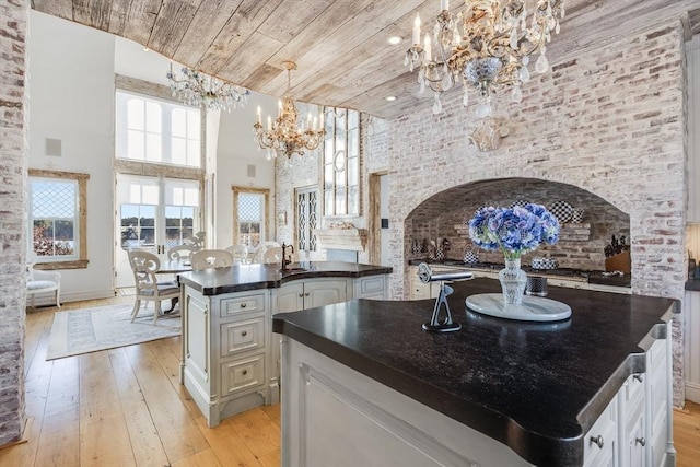 kitchen with wood ceiling, a towering ceiling, a chandelier, and a center island with sink