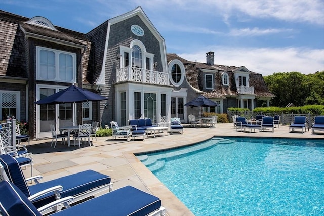 rear view of property featuring a fenced in pool and a patio