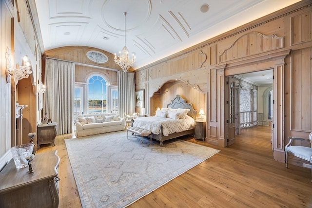 bedroom with an inviting chandelier, lofted ceiling, and light hardwood / wood-style floors