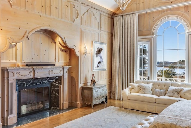 living room with a fireplace, wooden walls, wood-type flooring, and a high ceiling