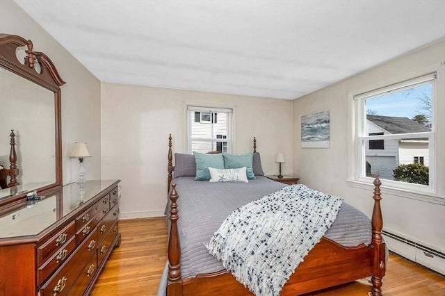 bedroom featuring multiple windows, light wood-type flooring, and a baseboard radiator