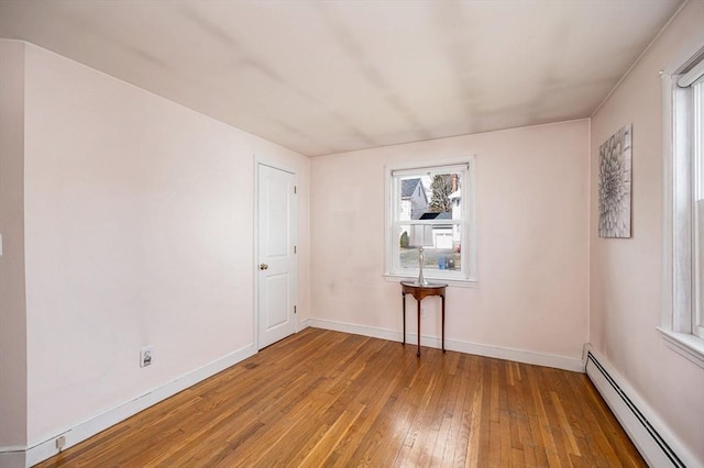 unfurnished room with a baseboard radiator, wood-type flooring, and baseboards