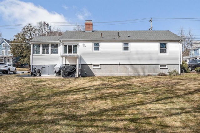 back of property with a chimney, a yard, and roof with shingles