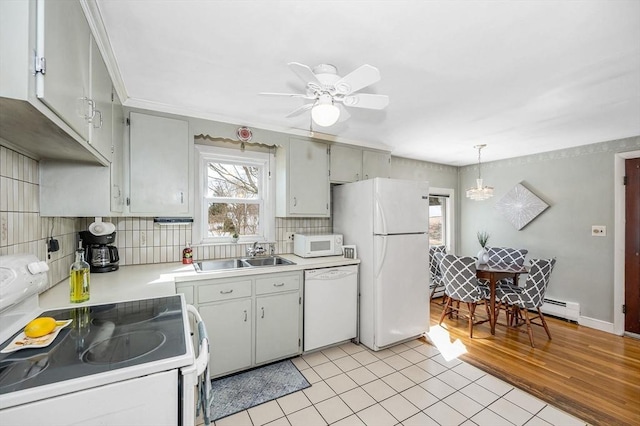 kitchen featuring white appliances, a sink, light countertops, decorative light fixtures, and tasteful backsplash