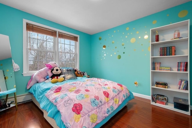 bedroom featuring baseboard heating, wallpapered walls, baseboards, and wood finished floors