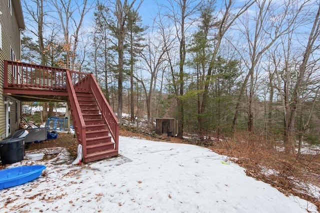 yard covered in snow featuring a deck and stairway