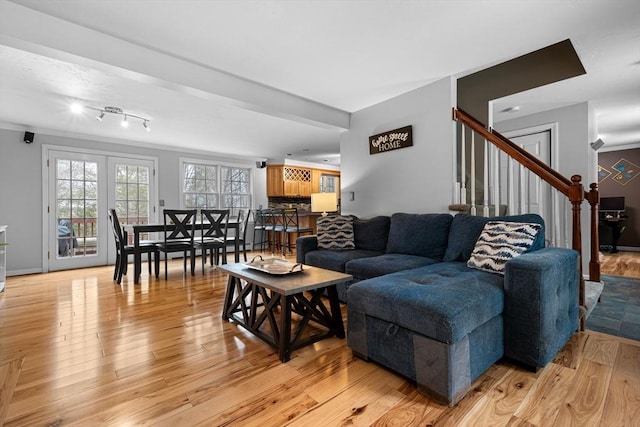 living room featuring light wood-style floors, ornamental molding, and stairway