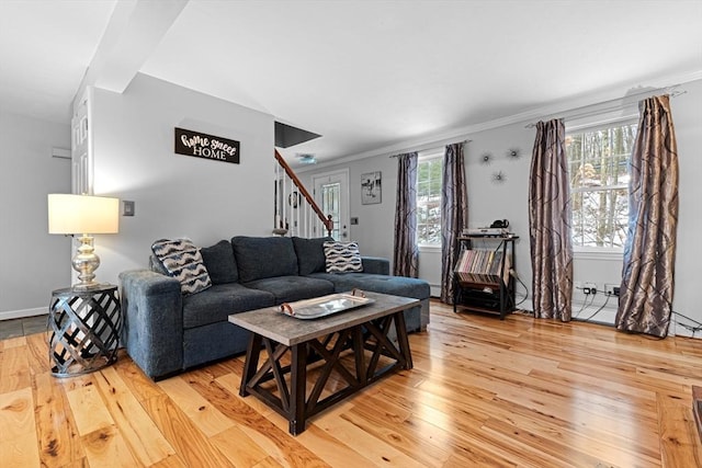 living area with stairs, light wood finished floors, and crown molding