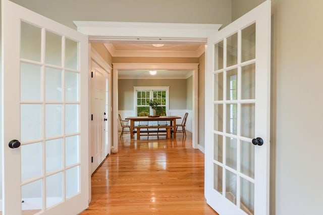 corridor featuring ornamental molding, light hardwood / wood-style floors, and french doors