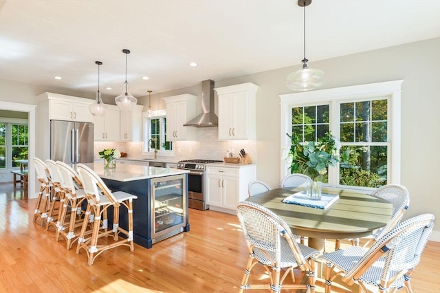 kitchen featuring beverage cooler, white cabinets, wall chimney exhaust hood, and stainless steel appliances