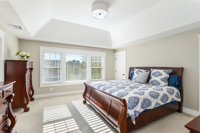 bedroom featuring a raised ceiling and light colored carpet