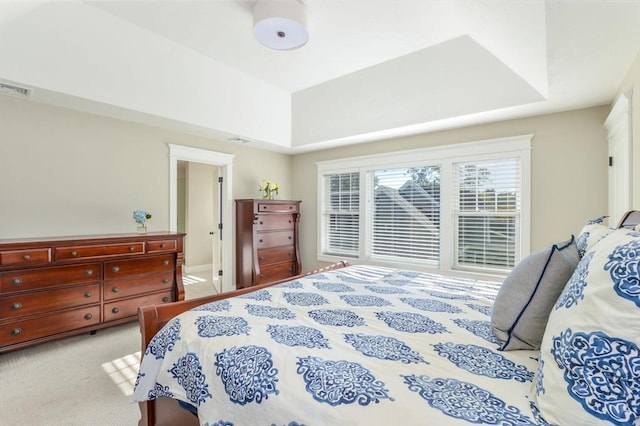 bedroom with a raised ceiling and light carpet