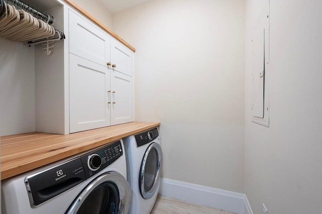 clothes washing area with baseboards, cabinet space, and washer and dryer