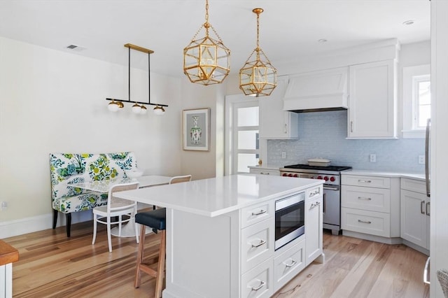 kitchen featuring light countertops, decorative backsplash, appliances with stainless steel finishes, and custom exhaust hood