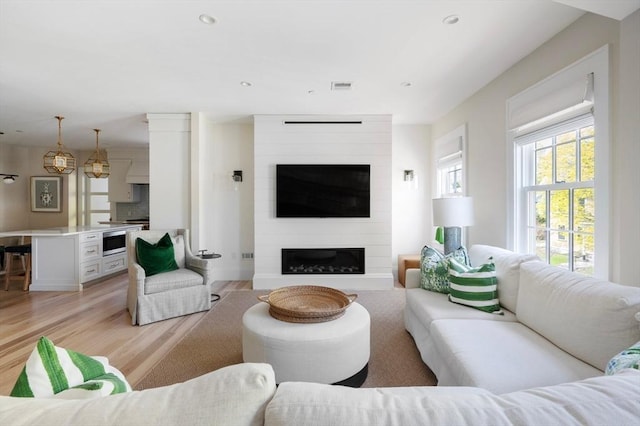 living room with light wood-style floors, recessed lighting, visible vents, and a large fireplace
