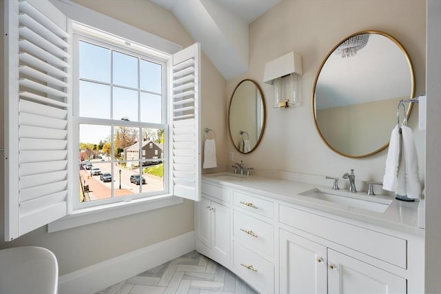 bathroom featuring a sink, baseboards, and double vanity