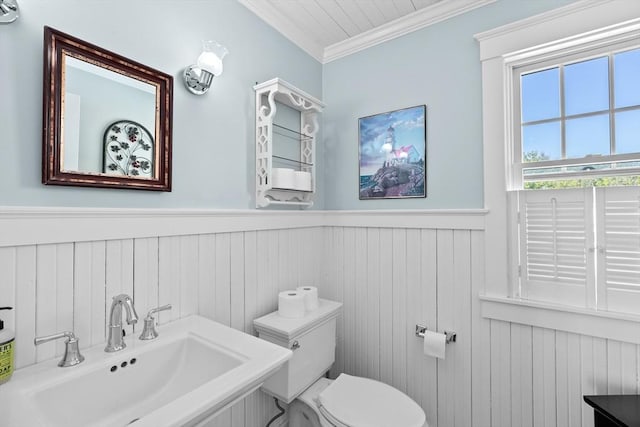 bathroom with toilet, ornamental molding, wood walls, and sink