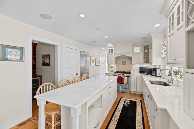 kitchen with white cabinets, a center island, stainless steel gas stove, sink, and a breakfast bar area