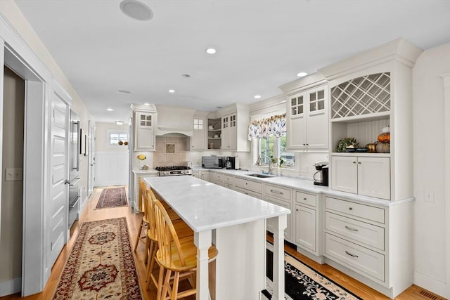 kitchen with a kitchen island, sink, stainless steel range, a breakfast bar area, and white cabinets