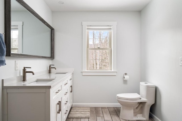 full bath with baseboards, a sink, toilet, and wood finished floors