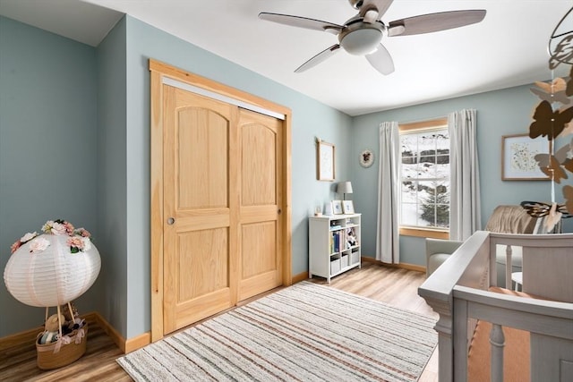 bedroom with a ceiling fan, a closet, light wood-style flooring, and baseboards