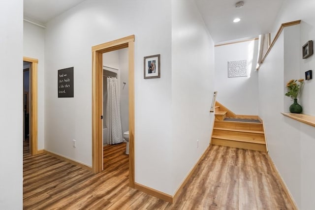 corridor featuring stairs, recessed lighting, baseboards, and wood finished floors