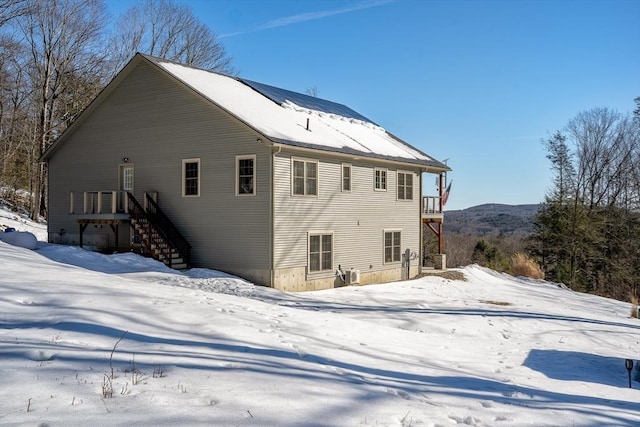 snow covered back of property with stairs