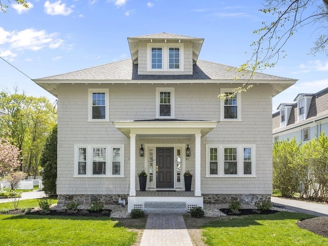 traditional style home featuring a shingled roof and a front lawn