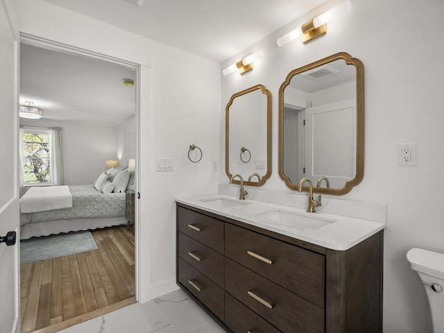 full bath with connected bathroom, double vanity, toilet, and a sink