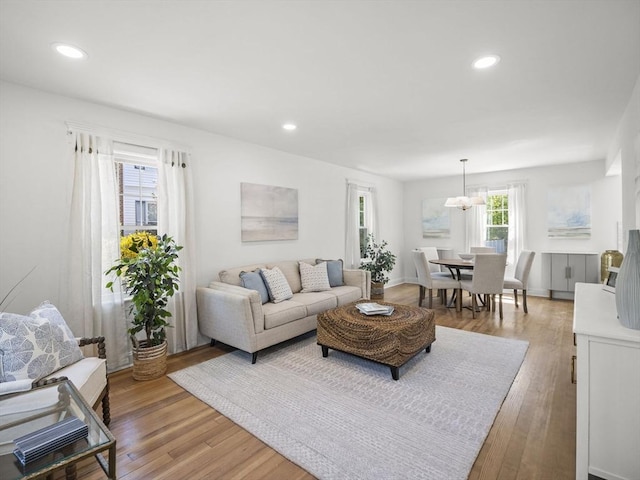 living area featuring light wood-style floors, recessed lighting, and an inviting chandelier
