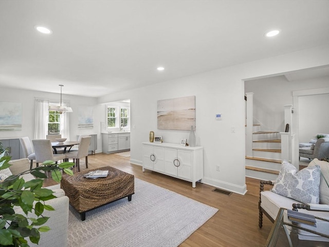living area featuring recessed lighting, light wood-type flooring, stairs, and visible vents
