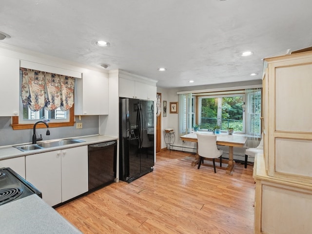 kitchen with light hardwood / wood-style floors, white cabinetry, black appliances, sink, and a baseboard heating unit