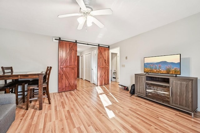 interior space with a barn door, ceiling fan, and light hardwood / wood-style floors