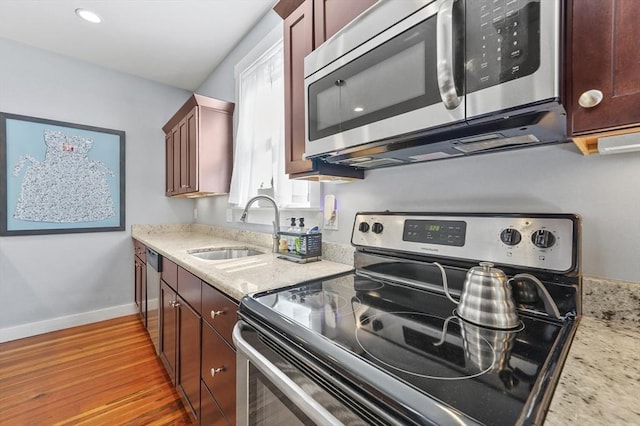 46 Converse Ave Unit 1, Malden, MA 02148 - kitchen with stainless steel appliances, a sink, wood finished floors, baseboards, and light stone counters